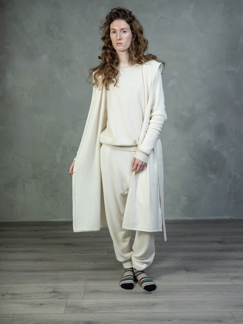 Female model wearing a Lynne Coleman cashmere jumper, hooded yacht wrap and jogger in colour cream